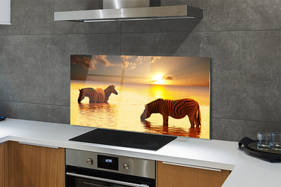 Painel de vidro Zebras na água do pôr do sol