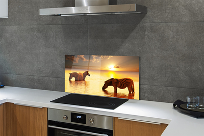 Painel de vidro Zebras na água do pôr do sol