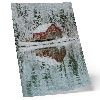 Arte de parede Uma cabana vermelha entre árvores cobertas de neve à beira da água.