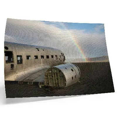 Poster em tela destroços de um avião de metal com um arco-íris ao fundo