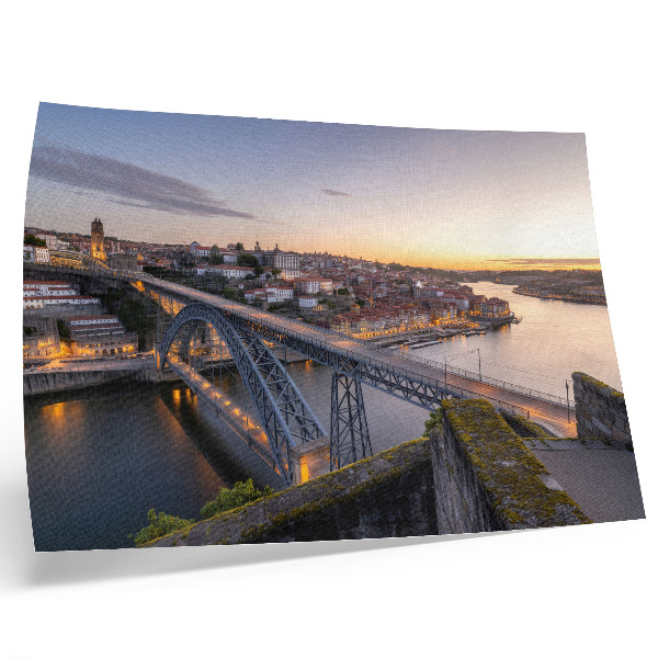 Poster A ponte com o pôr do sol e a cidade ao fundo.