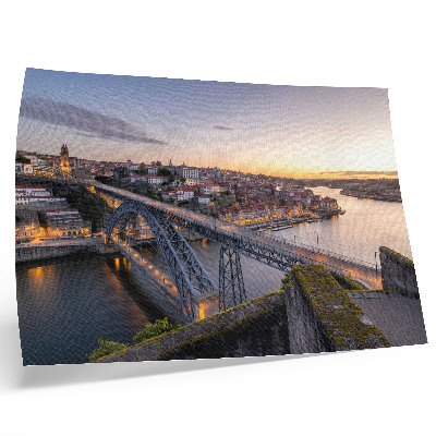 Poster A ponte com o pôr do sol e a cidade ao fundo.