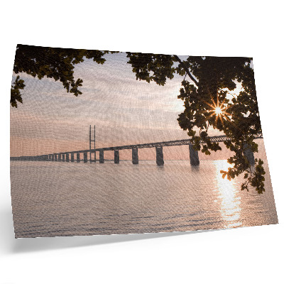 Poster em tela Uma ponte pitoresca ao pôr do sol sobre a água.