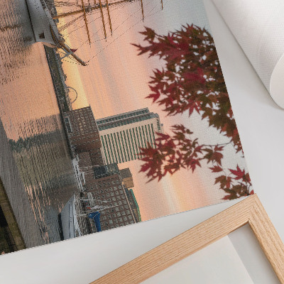 Poster Um veleiro ao pôr do sol, um panorama tranquilo da cidade.