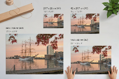 Poster Um veleiro ao pôr do sol, um panorama tranquilo da cidade.