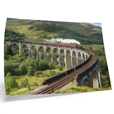 Poster Um viaduto com um trem entre colinas verdejantes.