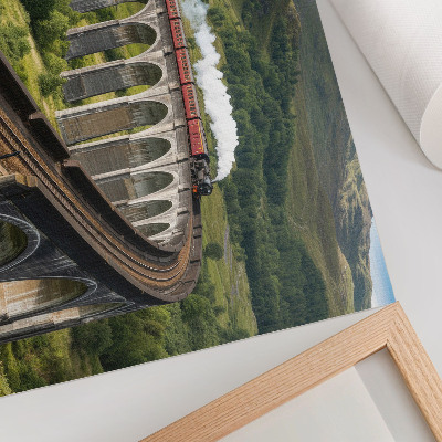 Poster Um viaduto com um trem entre colinas verdejantes.